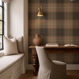 May include: A room interior featuring plaid wallpaper in shades of brown, tan, and dark gray. A wooden desk holds a brown ceramic pitcher and books. A gray upholstered chair with a skirt sits in front of the desk. A window seat has two beige pillows.