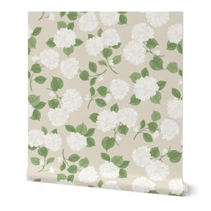 May include: Wallpaper roll with a repeating pattern of white hydrangea flowers and green leaves on a beige backdrop. The floral design is a classic and elegant choice for interior decor.