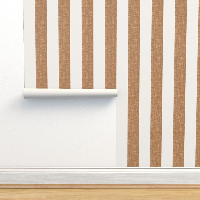May include: A roll of brown and white striped wallpaper with a textured surface. The wallpaper is partially unrolled and hanging on a white wall.