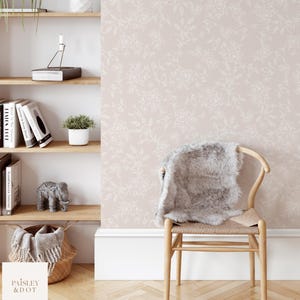Puede incluir: Un papel tapiz rosa p&aacute;lido con un delicado patr&oacute;n floral blanco. El papel tapiz se muestra en una habitaci&oacute;n con una silla de madera y una estanter&iacute;a.