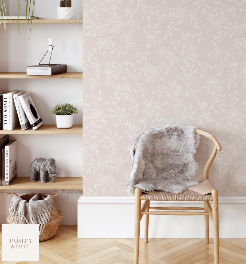 Puede incluir: Un papel tapiz rosa p&aacute;lido con un delicado patr&oacute;n floral blanco. El papel tapiz se muestra en una habitaci&oacute;n con una silla de madera y una estanter&iacute;a.