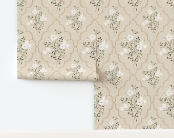 May include: Wallpaper roll featuring a repeating floral pattern. The design includes white flowers with green leaves and peach accents, set against a beige background with a gold-colored trellis design.