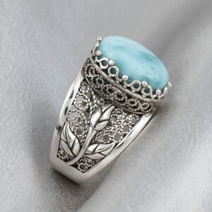 May include: A silver ring featuring a blue gemstone set in a filigree design.