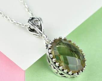 May include: A silver chain necklace with a pendant featuring a large, oval-shaped, faceted, green gemstone set in a silver filigree frame.