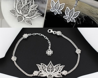 May include: A silver filigree lotus flower pendant necklace, a pair of silver filigree lotus flower earrings, and a silver filigree lotus flower bracelet.