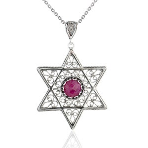 May include: A silver Star of David pendant necklace with a red gemstone in the center. The pendant is detailed with filigree work and hangs from a silver chain.