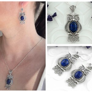 May include: A silver owl pendant necklace and earrings with blue gemstone accents. The owl is detailed with filigree and has a round blue gemstone in the center.