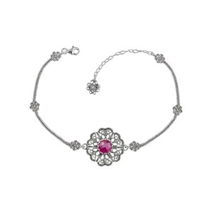 May include: A silver bracelet with a filigree design and a red gemstone in the center. The bracelet has a chain link extension.