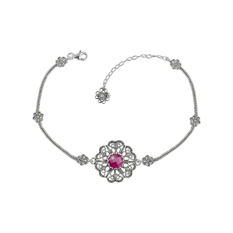 May include: A silver bracelet with a filigree design and a red gemstone in the center. The bracelet has a chain link extension.