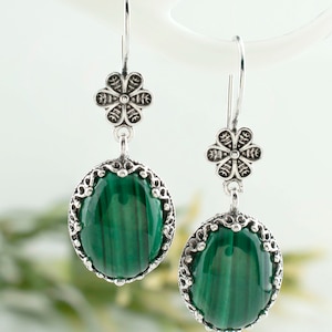 May include: A pair of silver earrings with green malachite stones and floral accents.