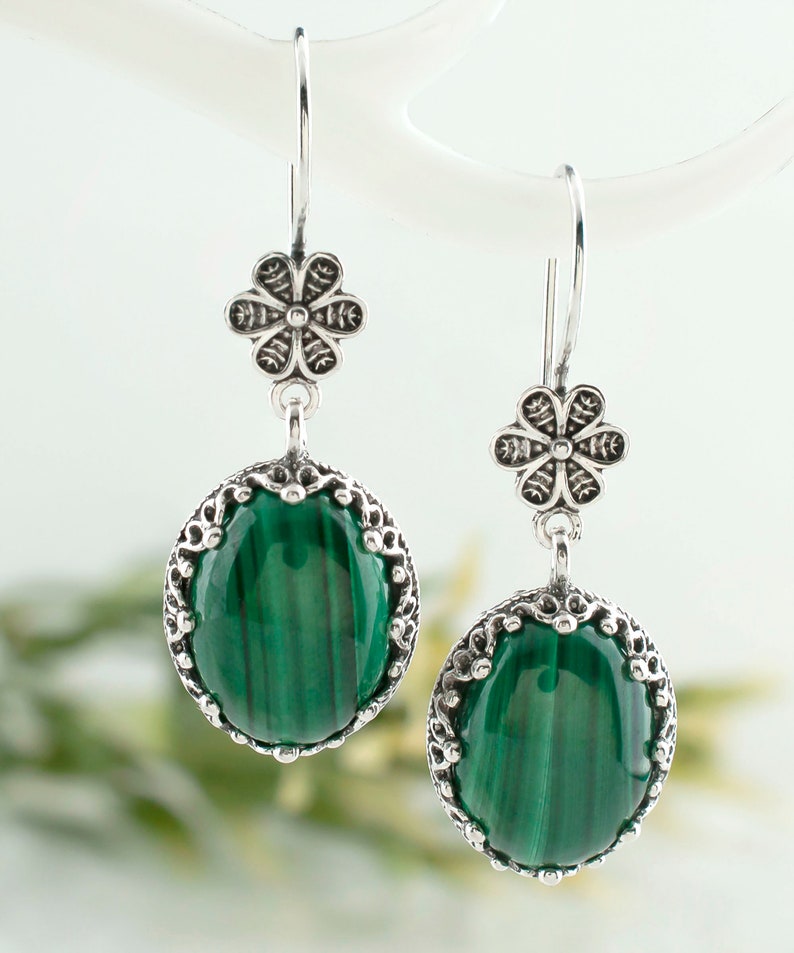 May include: A pair of silver earrings with green malachite stones and floral accents.
