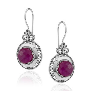 May include: A pair of silver earrings with a filigree design and a pink gemstone in the center.