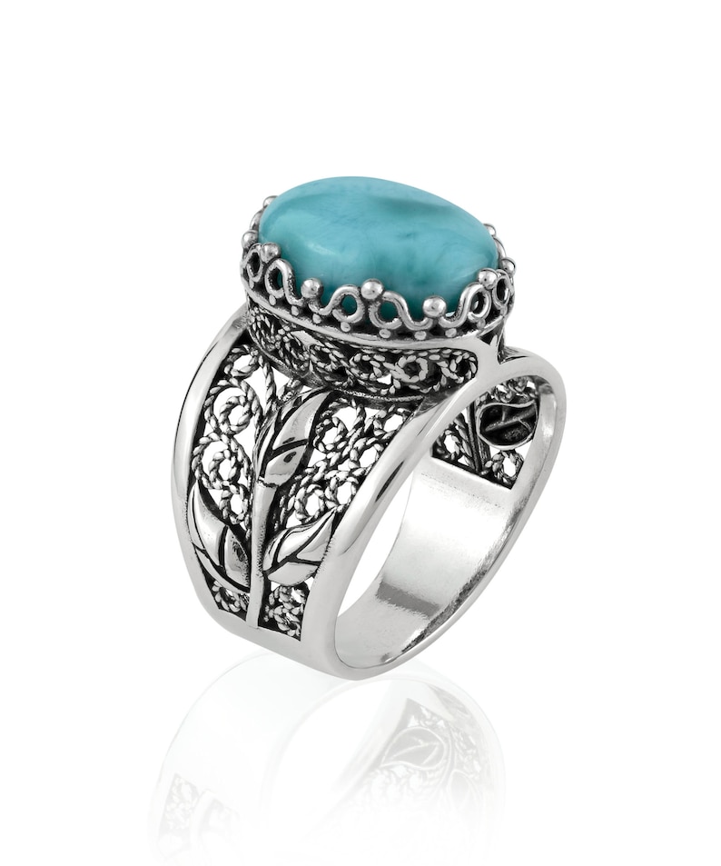 May include: A silver ring with a turquoise gemstone set in a filigree design.