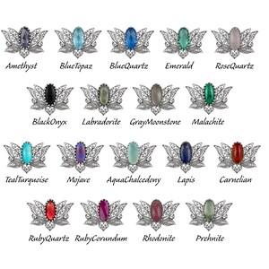 May include: A set of 16 silver filigree brooches with different colored gemstones. The brooches are shaped like a lotus flower with a gemstone in the center. The gemstones are amethyst, blue topaz, blue quartz, emerald, rose quartz, black onyx, labradorite, gray moonstone, malachite, teal turquoise, mojave, aqua chalcedony, lapis, carnelian, ruby quartz, ruby corundum, rhodonite, and prehnite.