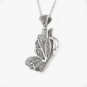 May include: A silver filigree butterfly pendant necklace. The butterfly is detailed and intricate, with a delicate chain.