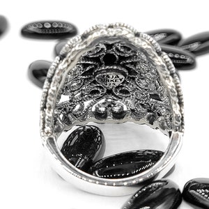May include: A silver ring with an intricate filigree design. The inside of the ring is stamped with "JAJA TURKEY 925".