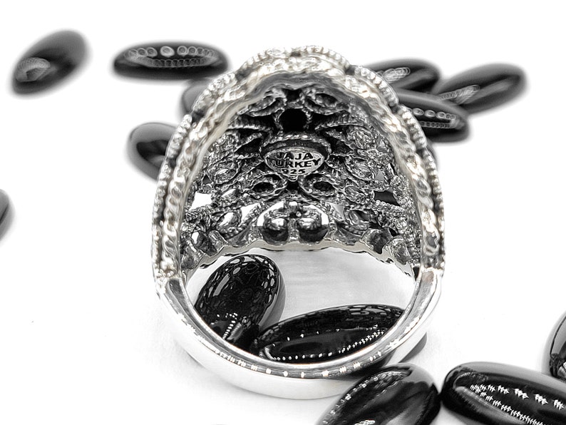 May include: A silver ring with an intricate filigree design. The inside of the ring is stamped with "JAJA TURKEY 925".