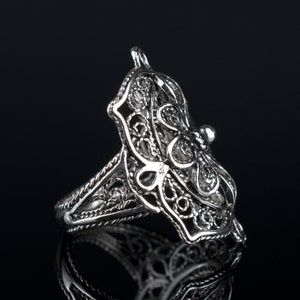 May include: A silver filigree ring with a delicate butterfly design. The ring is made of intricate, openwork metal and has a smooth, polished finish.