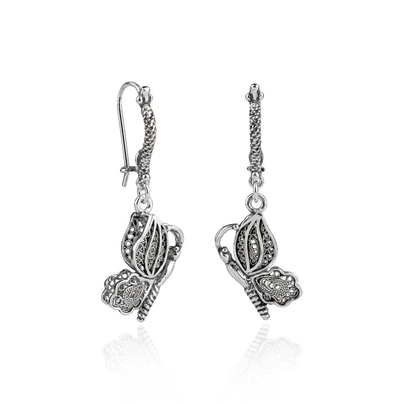 May include: Silver filigree butterfly dangle earrings. The earrings feature a delicate butterfly design with intricate details.