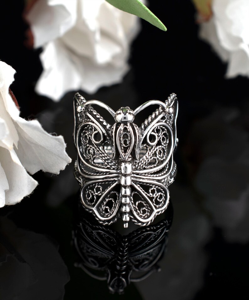 May include: A silver filigree butterfly ring. The ring is detailed with intricate designs and has a delicate, feminine look.