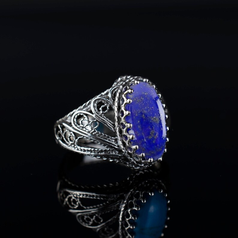 May include: A silver ring featuring an oval lapis lazuli gemstone set in a filigree design.
