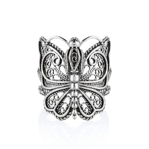 May include: A silver filigree butterfly ring. The ring is made of intricate, detailed work and has a delicate, feminine design.