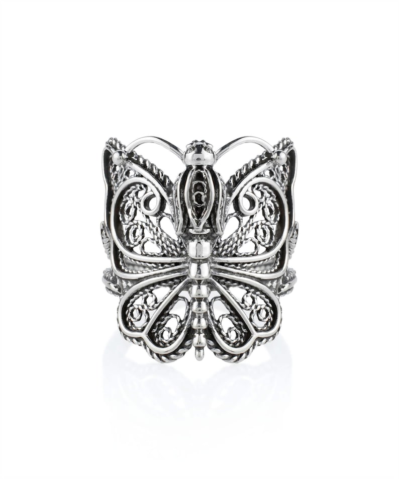 May include: A silver filigree butterfly ring. The ring is made of intricate, detailed work and has a delicate, feminine design.