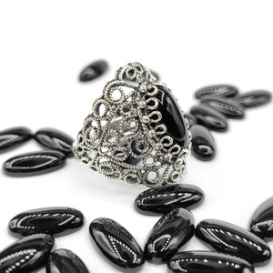 May include: A silver ring with a black oval gemstone set in a filigree design.