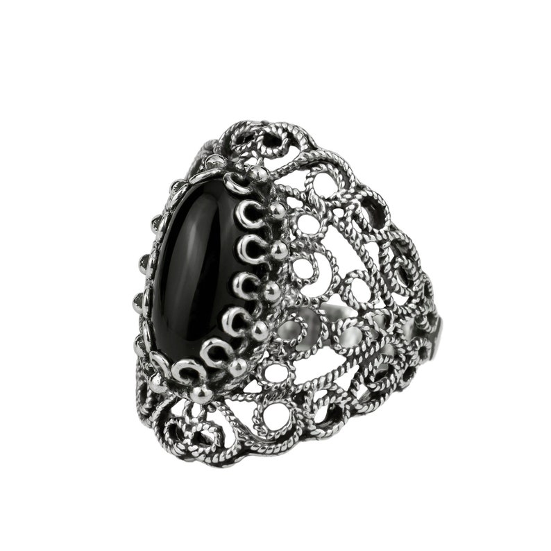 May include: A silver ring with a black oval gemstone set in a filigree design.
