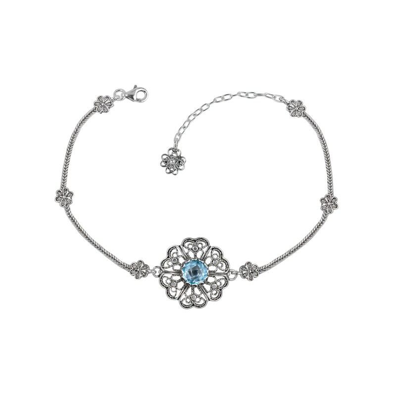 May include: A silver bracelet with a delicate chain and a large, ornate pendant featuring a blue gemstone surrounded by filigree details.