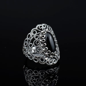 May include: A silver ring with a black gemstone set in a filigree design.