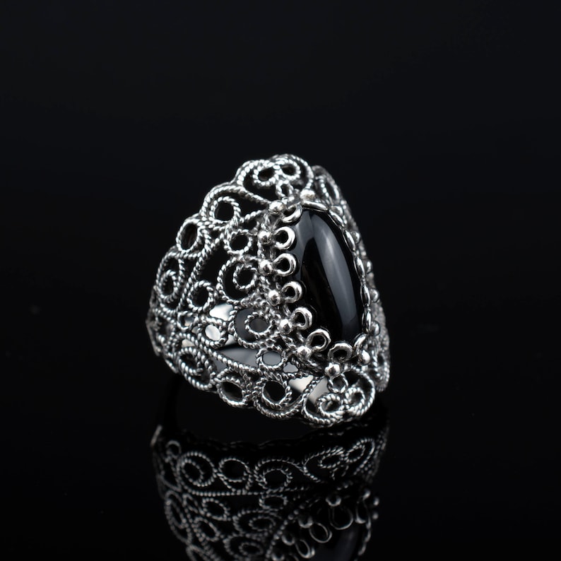 May include: A silver ring with a black gemstone set in a filigree design.