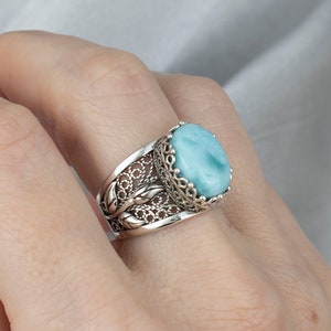 May include: A silver ring featuring a blue and white gemstone set in a filigree design.