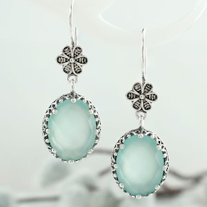 May include: Silver dangle earrings with a light blue gemstone and a silver flower charm.