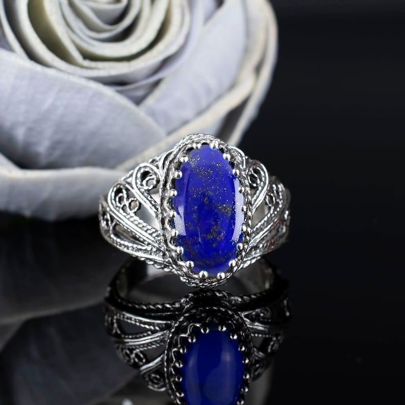 May include: A silver ring featuring an oval lapis lazuli gemstone set in a filigree design.