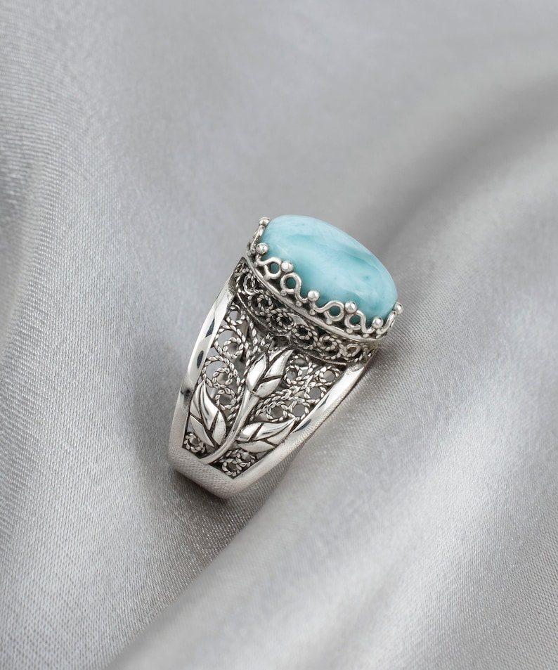 May include: A silver ring featuring a blue gemstone set in a filigree design.
