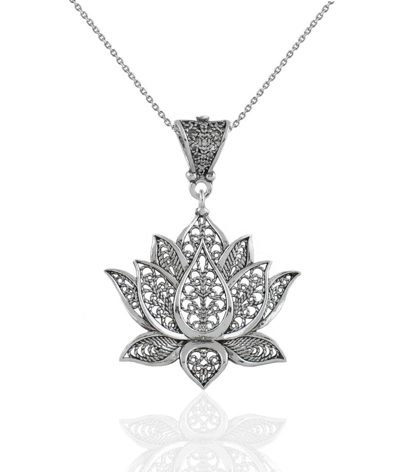 May include: Silver filigree lotus flower pendant necklace. The pendant is detailed with intricate cutouts and hangs from a delicate silver chain.