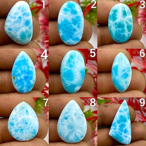 May include: A collection of nine polished Larimar gemstones in various shapes, including teardrop, oval, and marquise cuts. Each stone displays a distinct sky-blue and white marbled pattern, numbered one through nine, showcasing natural variations.