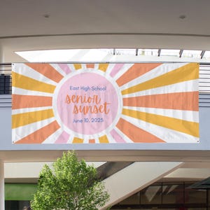 Op de afbeelding: Een rechthoekige banner met een zonnestraalpatroon in tinten oranje, geel en roze. Een centrale roze cirkel bevat de blauwe tekst East High School, de oranje cursieve tekst senior sunset en de blauwe datum 10 juni 2025.