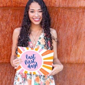 Teen girl holding a Last First Day sign or photo prop for the class of 2026, sunrise design in pink and orange