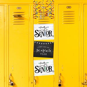 May include: A row of bright yellow metal school lockers with three stacked rectangular signs. The top and bottom signs feature the text finally a SENIOR 2027. The middle sign is black with white text reading FIRST DAY OF senior YEAR.