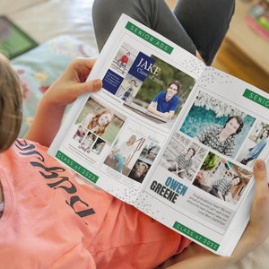 Teen holding an open high school yearbook on her lap looking at senior ads