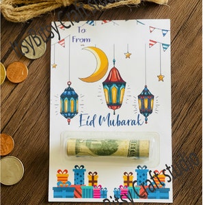 May include: A white card with a crescent moon and lanterns, the text "Eid Mubarak" and a rolled up dollar bill inside a clear plastic sleeve. The card is decorated with colorful gift boxes and red, white, and blue bunting.