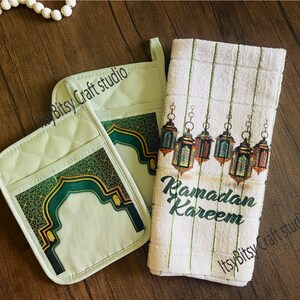 May include: Two green and gold pot holders with an arch design and the text "Itsy Bitsy Craft studio" and a white kitchen towel with green stripes and the text "Ramadan Kareem" and hanging lanterns.