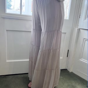 May include: A pair of light beige wide-leg pants with a tiered ruffle design. The pants have a relaxed fit and a flowy silhouette.