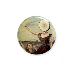 Puede incluir: Un bot&oacute;n de estilo vintage que presenta a una mujer con un objeto grande, redondo y blanco que le cubre la cara. Lleva un vestido rojo con estrellas blancas y est&aacute; de pie en una playa con un ni&ntilde;o en el fondo. La escena est&aacute; pintada en colores apagados y tiene un aire nost&aacute;lgico.