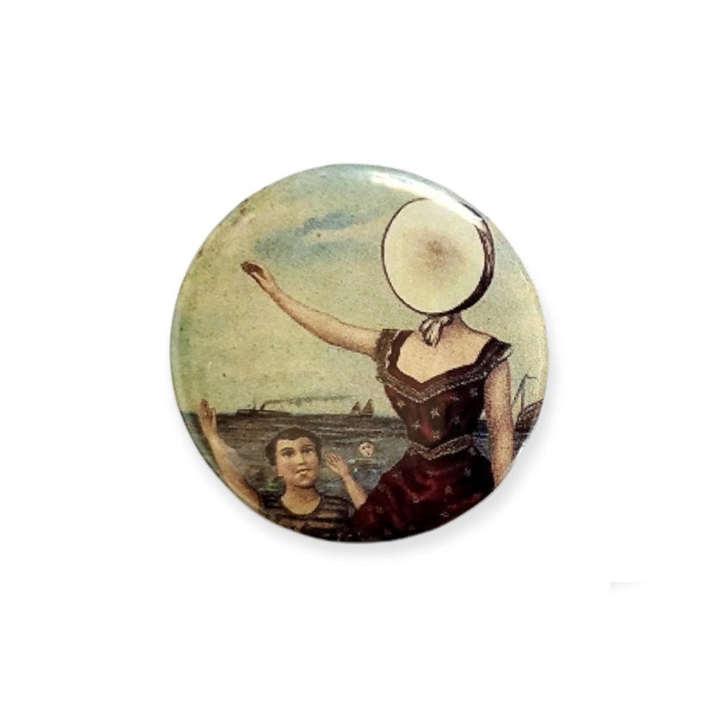 Puede incluir: Un bot&oacute;n de estilo vintage que presenta a una mujer con un objeto grande, redondo y blanco que le cubre la cara. Lleva un vestido rojo con estrellas blancas y est&aacute; de pie en una playa con un ni&ntilde;o en el fondo. La escena est&aacute; pintada en colores apagados y tiene un aire nost&aacute;lgico.