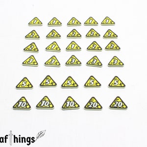 Puede incluir: Un conjunto de 20 piezas de juego de forma triangular amarilla con contornos negros y números blancos. Los números van del 1 al 20.