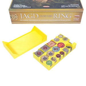 May include: A board game called "Jagd Nach Dem Ring" with a yellow organiser. The box is brown and gold with German text. The organiser holds game pieces, including coins and cards. The game is for 2-5 players, ages 12 and up.