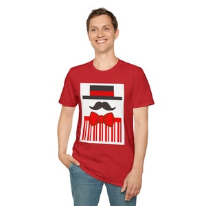 May include: Red t-shirt featuring a graphic design of a black hat, mustache, and red bow tie. The design is set against a white background with red and white vertical stripes. The shirt is worn by a person.